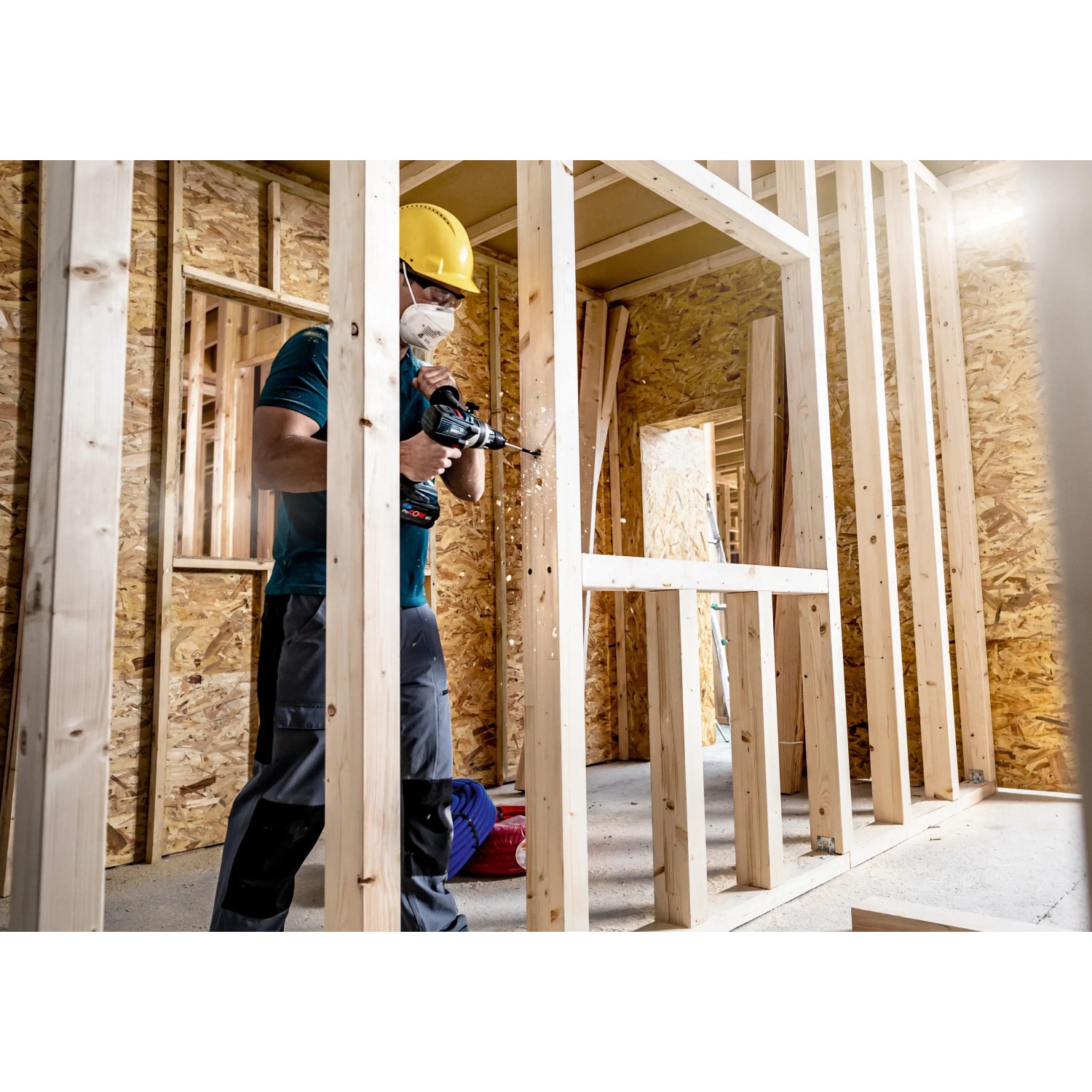 Handwerker bohrt mit Bosch Expert Flachfräsbohrer ein Loch in eine Holzwand.
