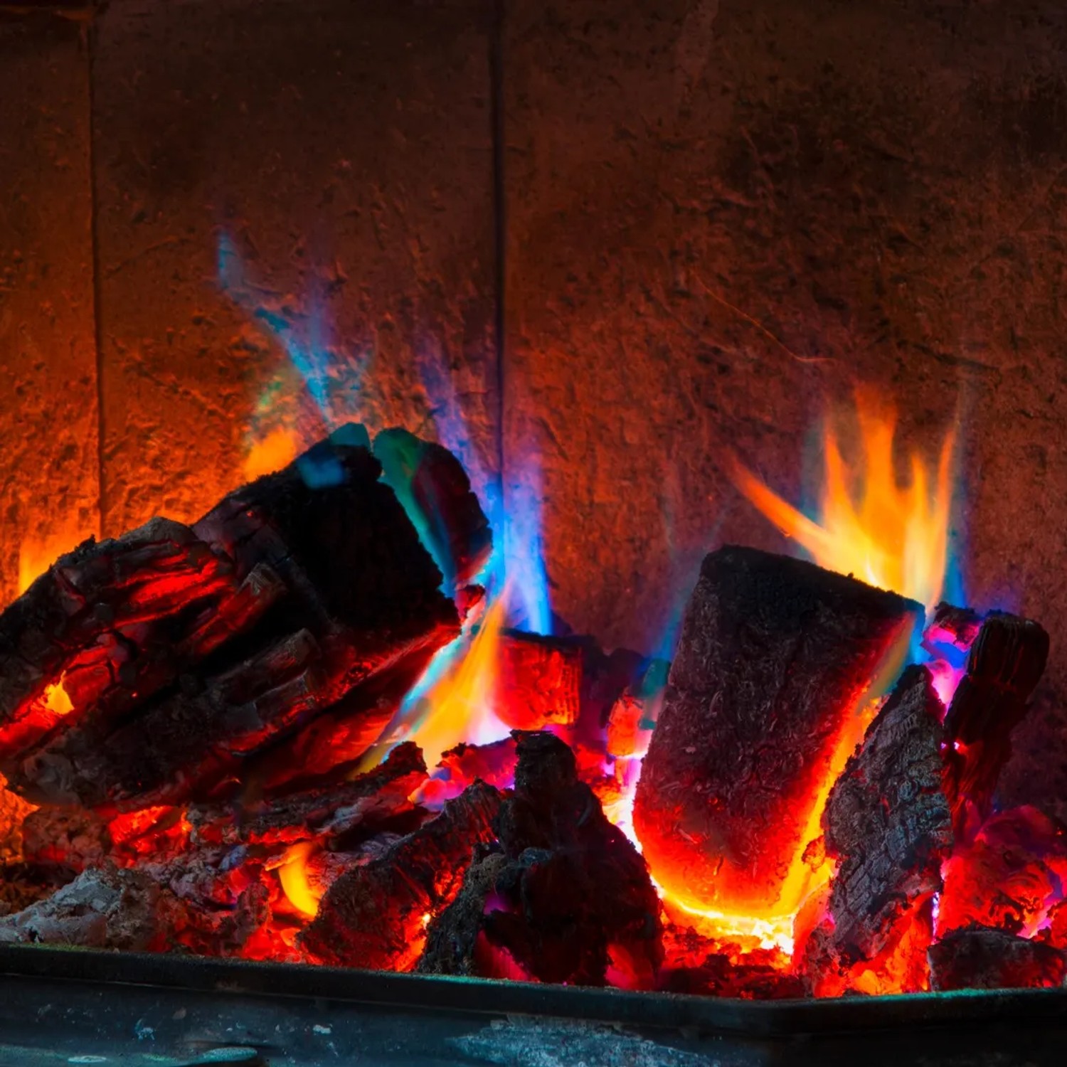 Buntes Feuer mit Feuerfarbe: Holzscheite mit roten, blauen und gelben Flammen im Kamin.