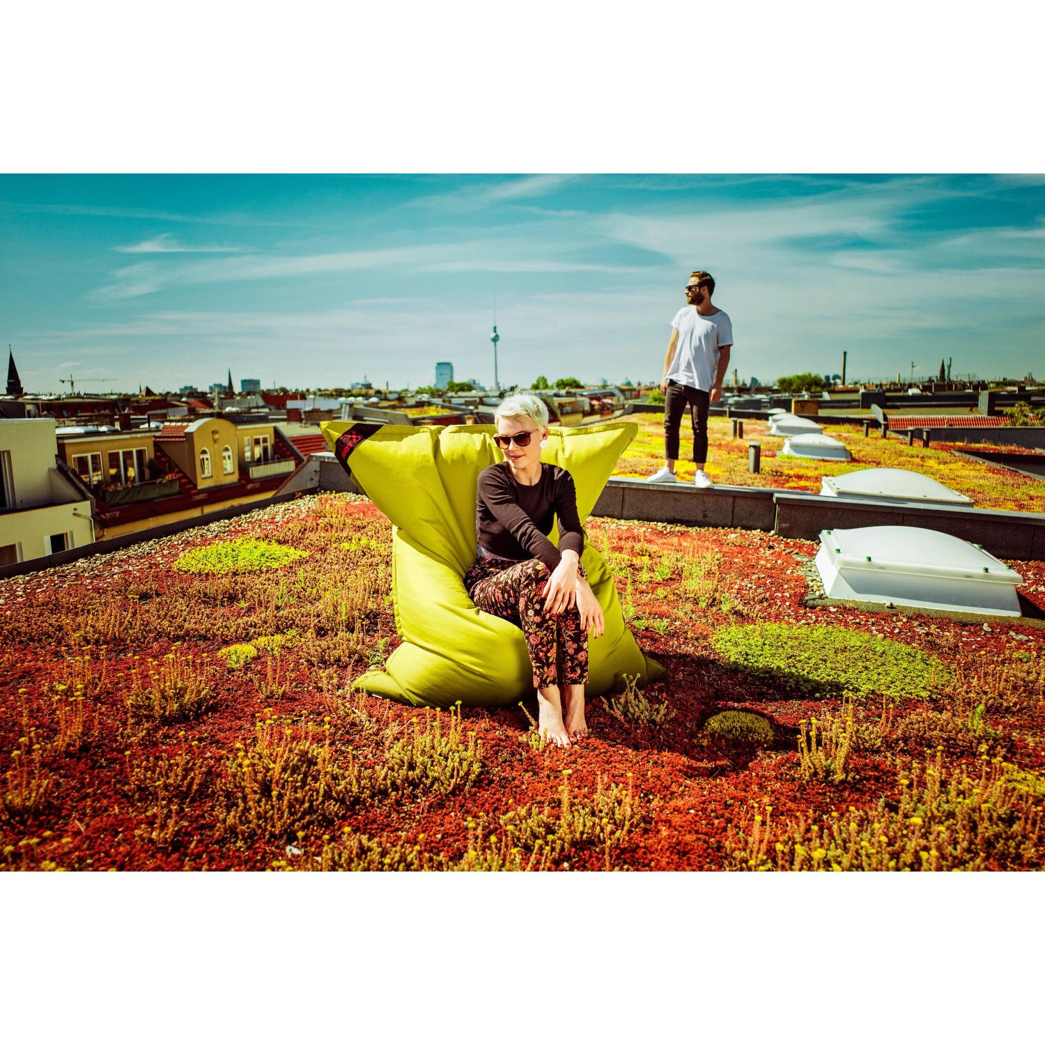 Grüner Sitting Point Sitzsack Big Foot Scuba (380 l) auf Dachterrasse mit Person.