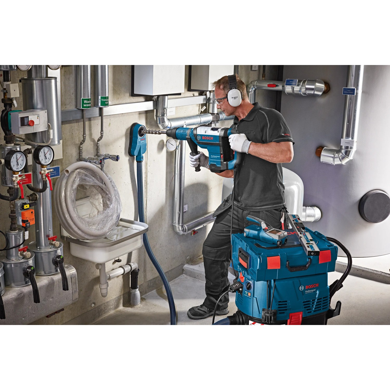 Anwendung der Bosch Professional GDE 68 Staubabsaugung mit Bohrhammer an einer Wand.