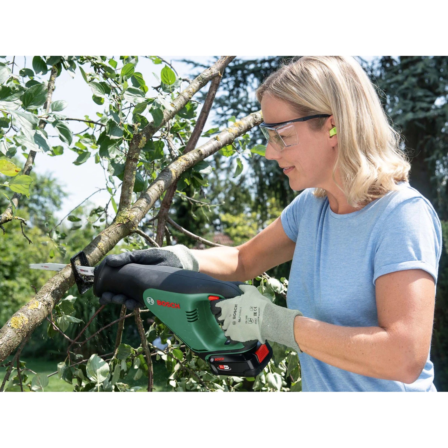 Frau sägt Ast mit Bosch 18V Akku-Säbelsäge AdvancedRecip 18. Inkl. Akku & Ladegerät.