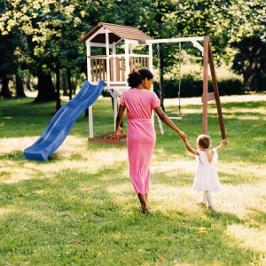 Axi Beach Tower Spielturm mit Rutsche und Schaukel, Mutter und Kind im Garten.
