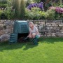 Grüner Garantia Thermo-Star Komposter 600 l mit Frau bei der Befüllung im Garten.