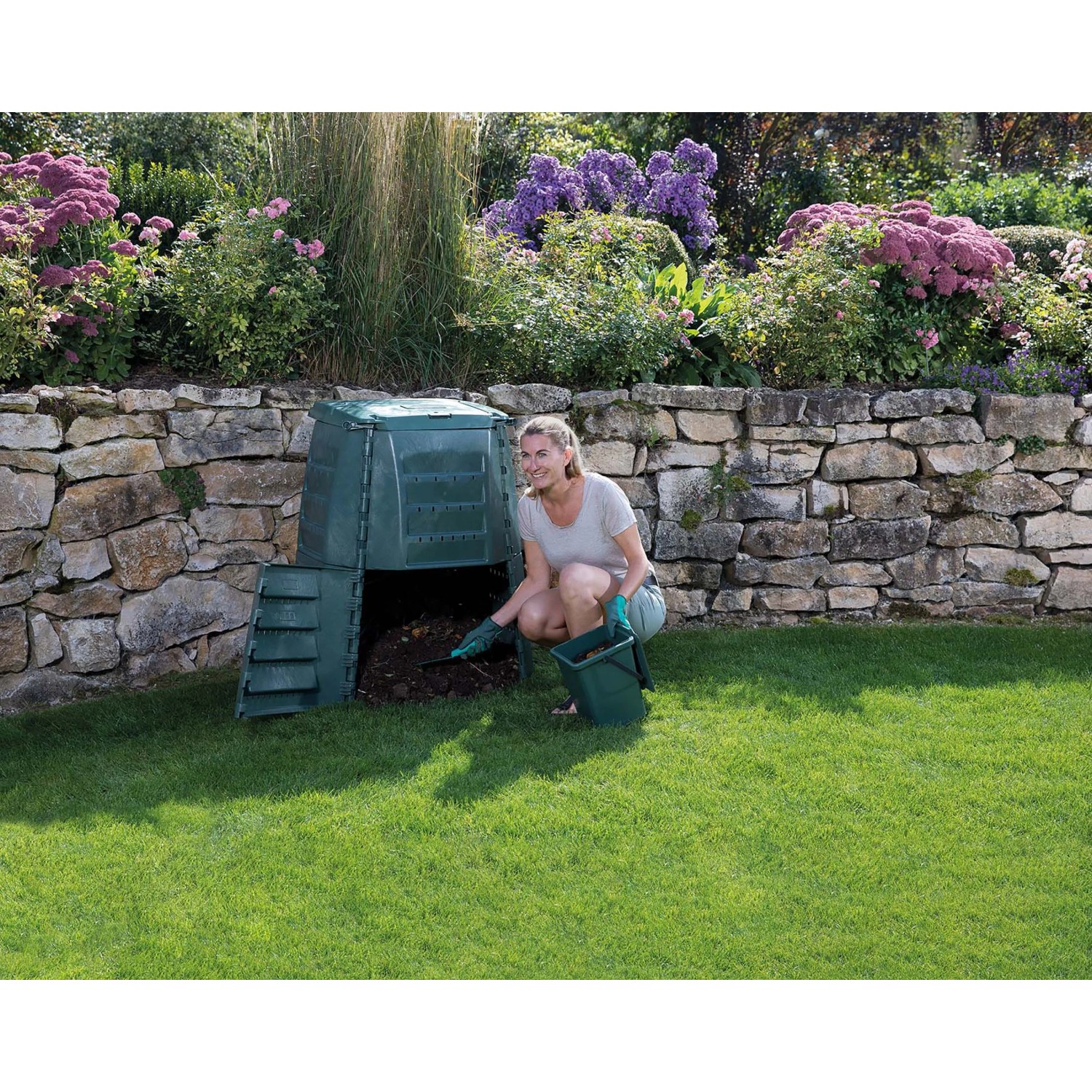 Grüner Garantia Thermo-Star Komposter 600 l mit Frau bei der Befüllung im Garten.