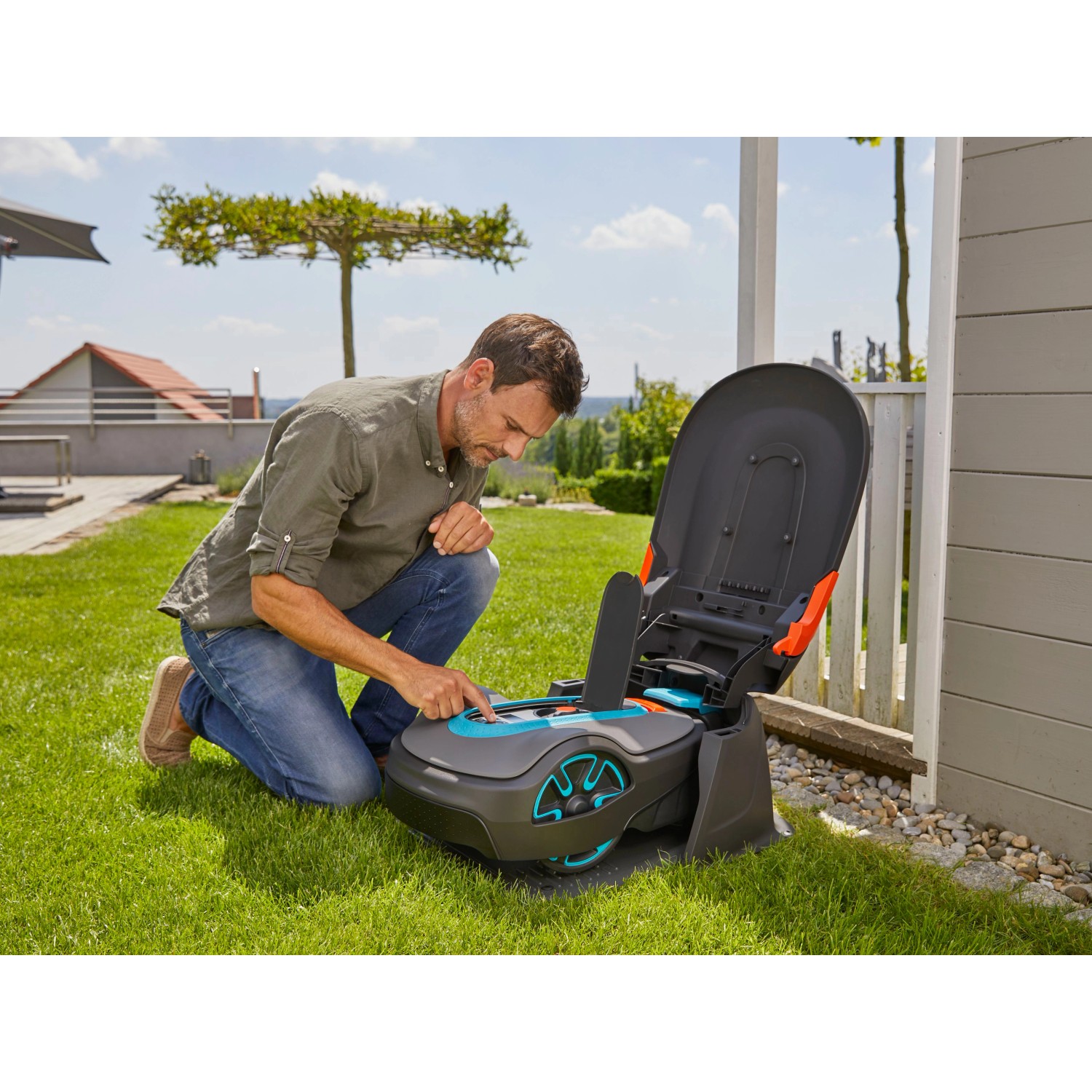 Gardena Mähroboter Garage für Sileno city/life mit Mann bei Bedienung im Garten.