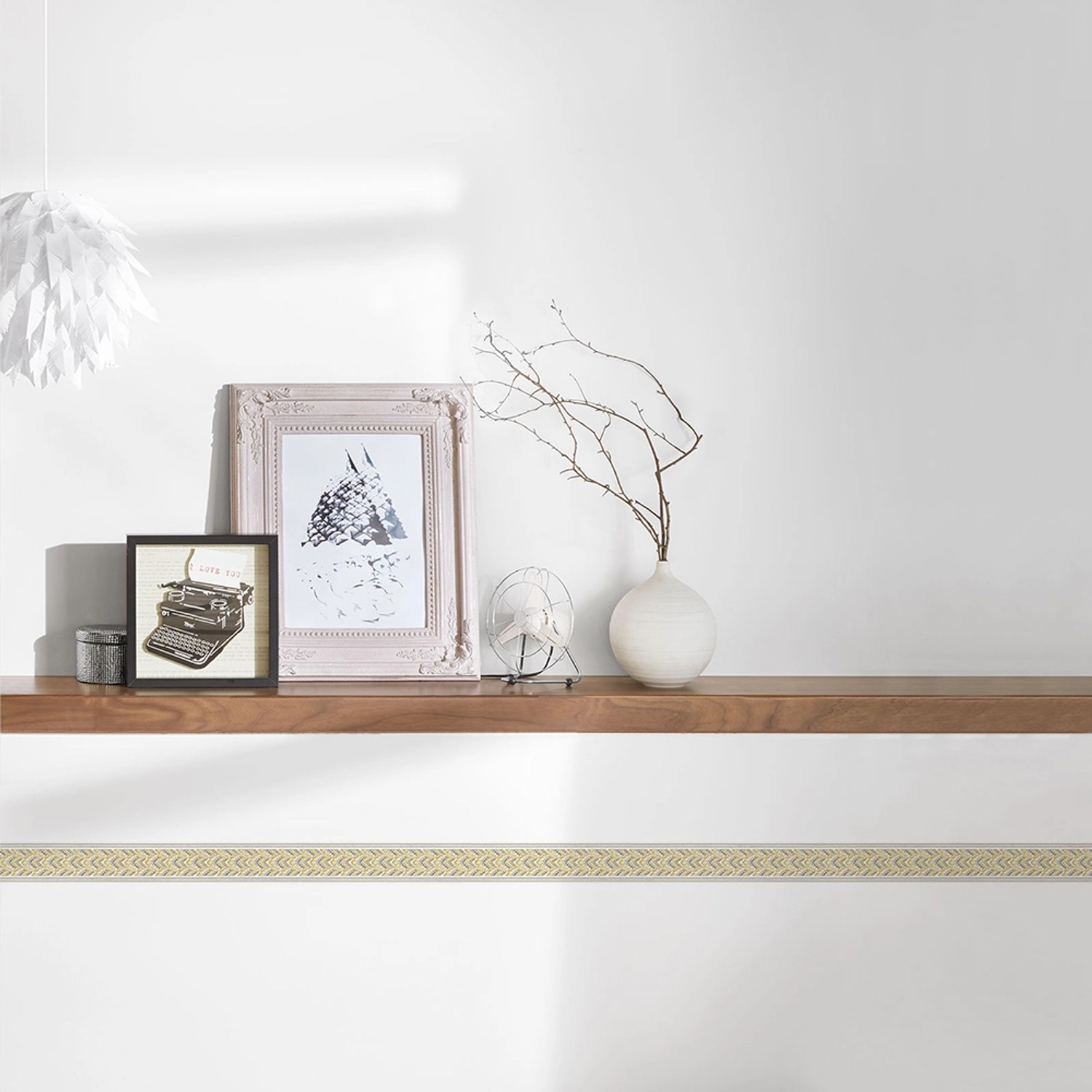 Selbstklebende A.S. Création Borte in Gold und Silber mit Muster, angebracht an einer weißen Wand.