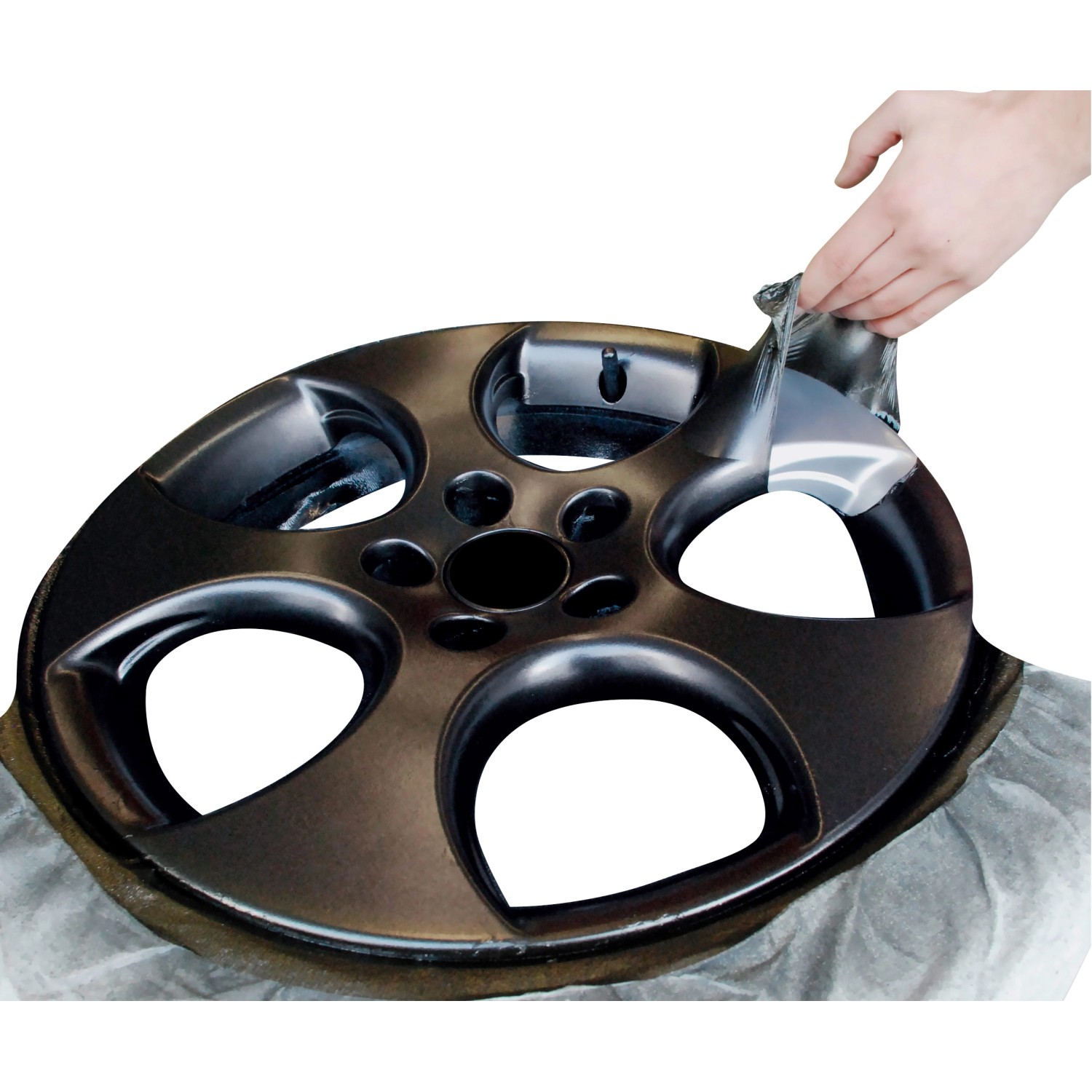 Felge mit Foliatec Sprühfolie in Matt-Schwarz, die abgezogen wird.