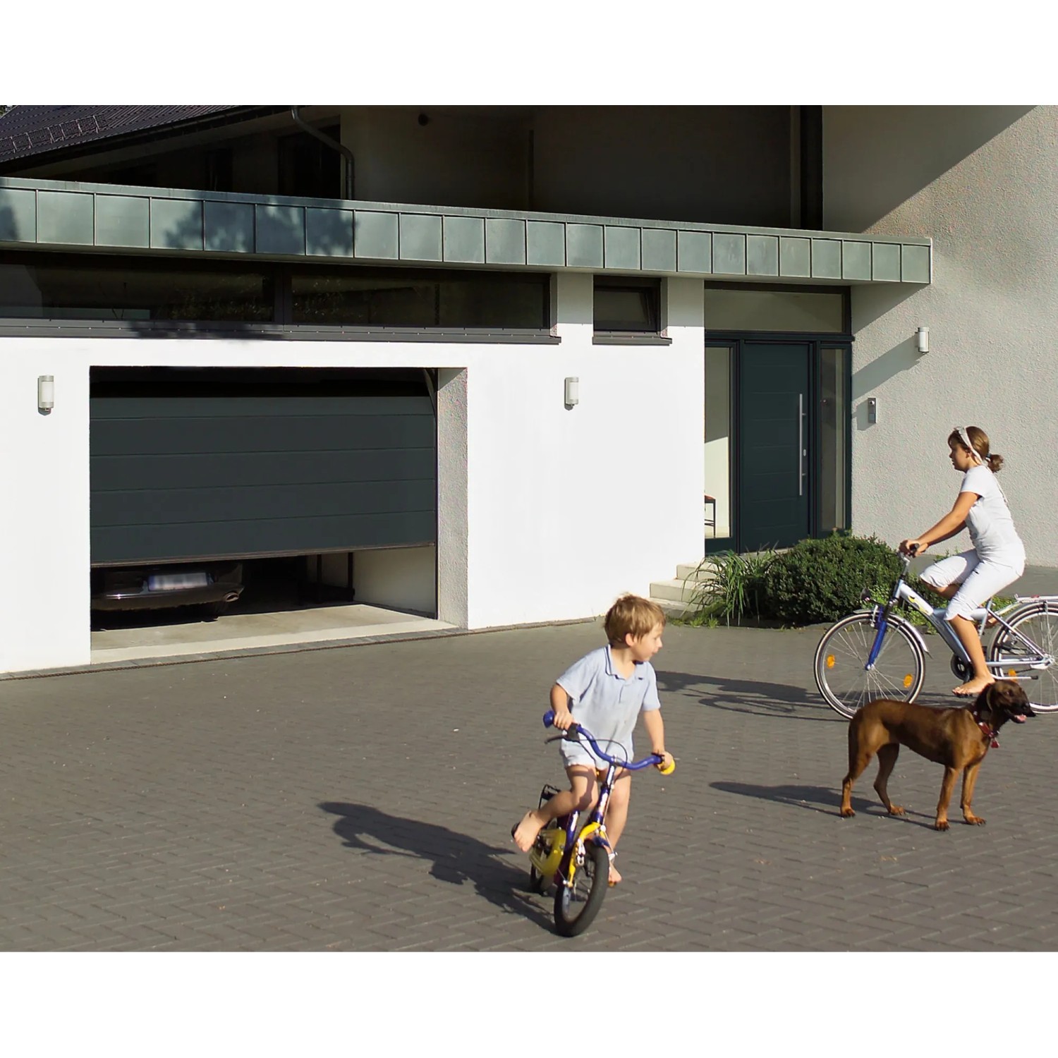 EcoStar Garagen-Sektionaltor, 2500x2000 mm, Anthrazitgrau, teilweise geöffnet. Familie vor Garage.