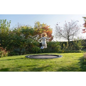 Schwarzes Exit InTerra Bodentrampolin (Ø 244 cm) mit springender Person im Garten.