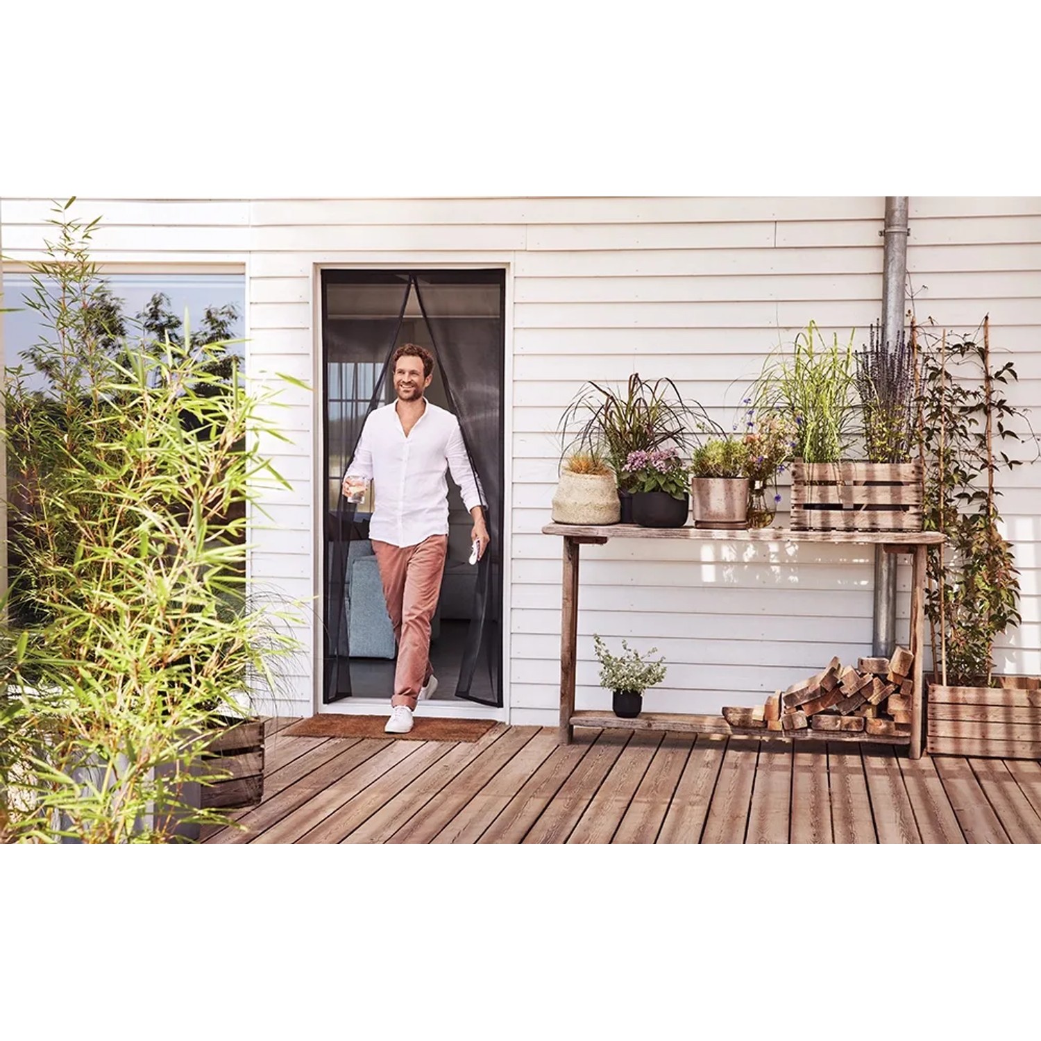 Mann geht durch tesa Magnetvorhang Anthrazit. Insektenschutz für Balkon- und Terrassentüren.