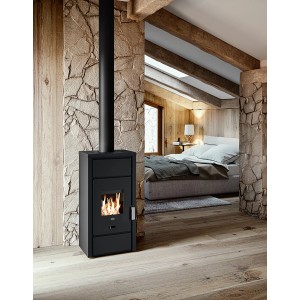 Schwarzer Blaze Kaminofen Ester 6 kW im Wohnraum mit Holzwand und Bett im Hintergrund.