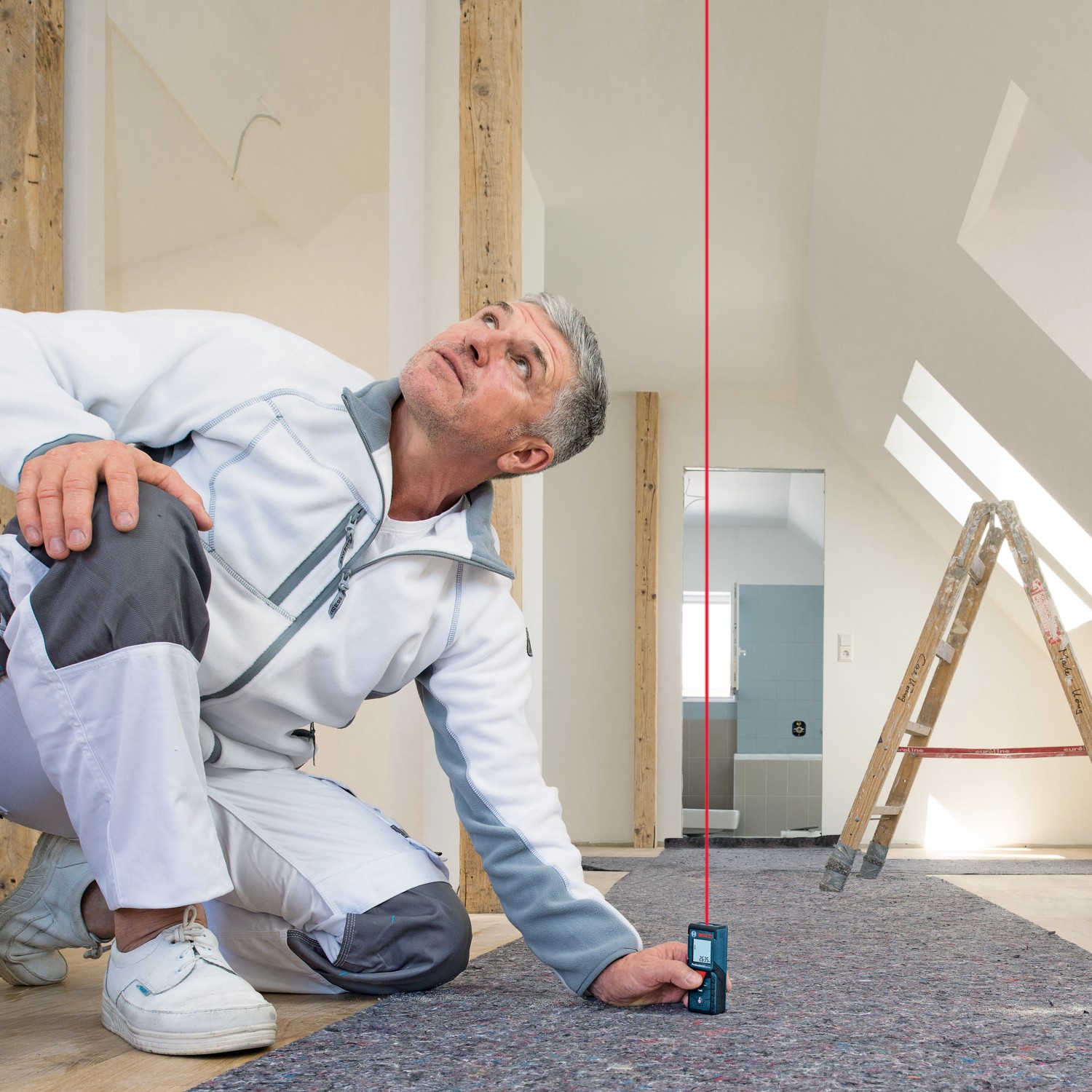 Handwerker misst Raumhöhe mit Bosch Professional Laser-Entfernungsmesser GLM 40.