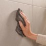 Hand wischt mit Tuch über Fliesen. Geeignet zur Montage der Tesa WC-Bürstengarnitur Moon.
