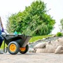 Schwarze Polar Schubkarre Cub Cart (127x71cm) mit gelben Rädern und Gartenabfällen. Ideal für Bau und Garten.