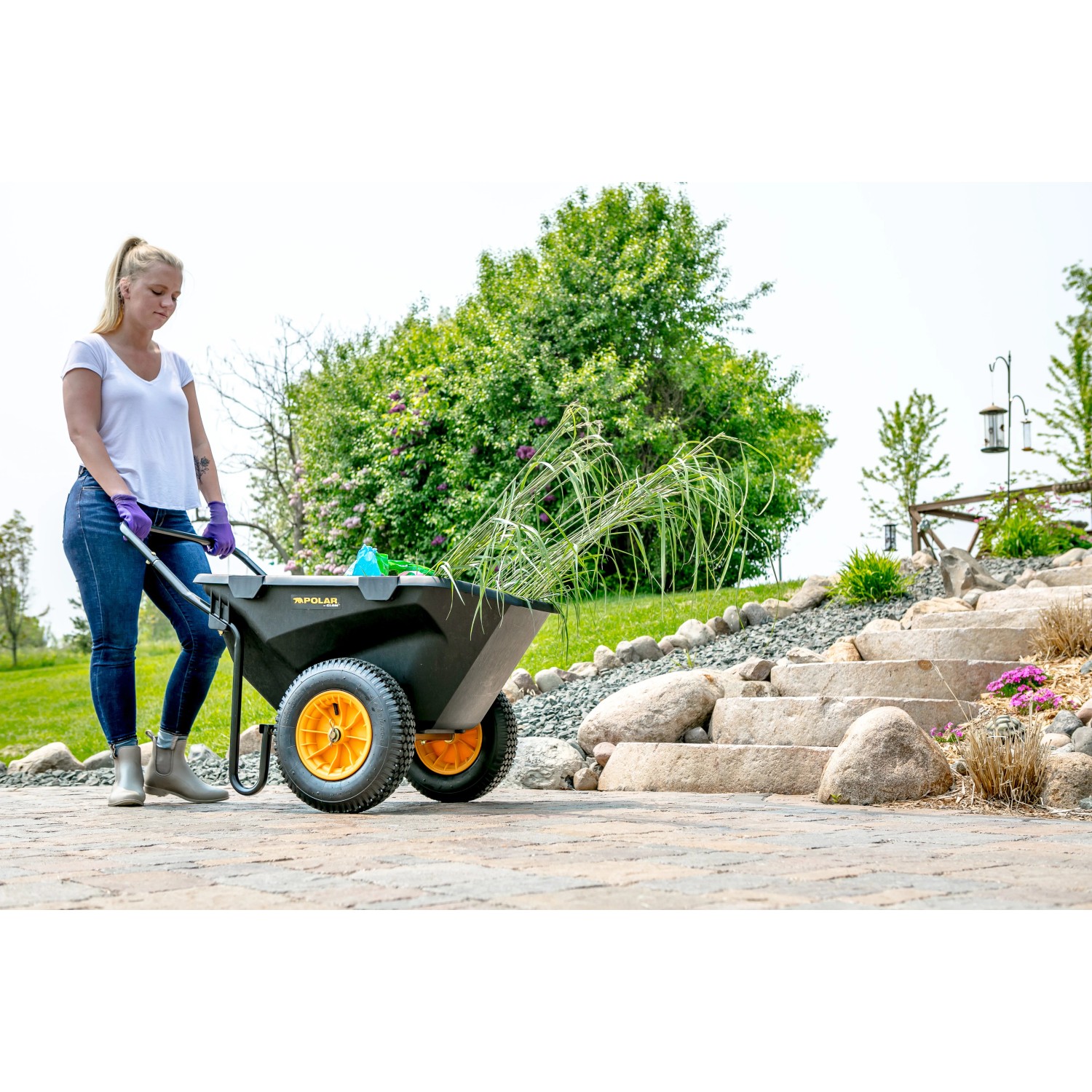 Schwarze Polar Schubkarre Cub Cart (127x71cm) mit gelben Rädern und Gartenabfällen. Ideal für Bau und Garten.