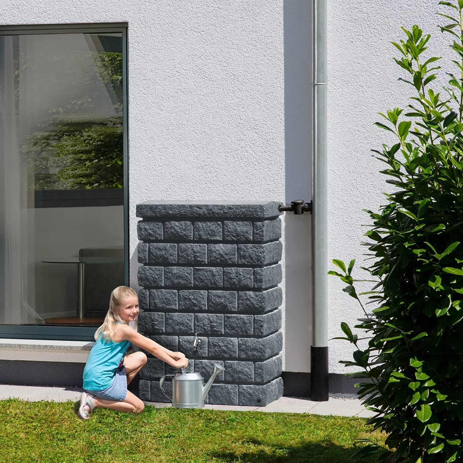 Garantia Wandtank Rocky Junior 300 l Dark Granite mit Mädchen und Gießkanne vor Hauswand.