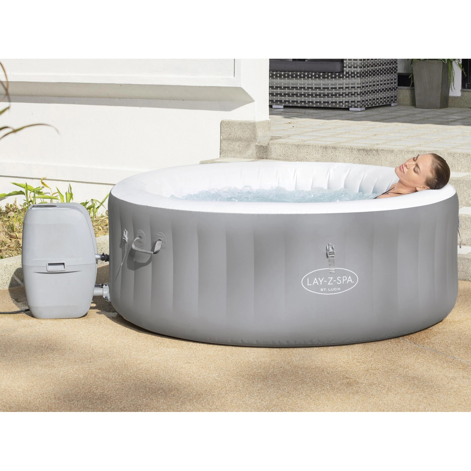 Bestway Lay-Z-Spa St. Lucia AirJet aufblasbarer Whirlpool in Grau mit Frau im Wasser.