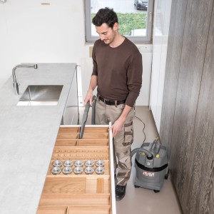 Mann saugt Schublade mit Kärcher Nass-Trockensauger ProNT 600 L. Staubklasse L.