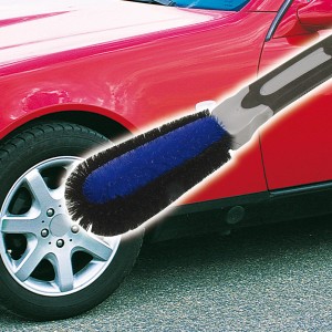 APA Felgenbürste mit blau-schwarzen Borsten und gummiertem Griff reinigt eine silberne Felge.