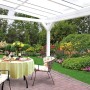 Freistehende, weiße Skan Holz Terrassenüberdachung Sanremo mit Tisch und Stühlen im Garten.