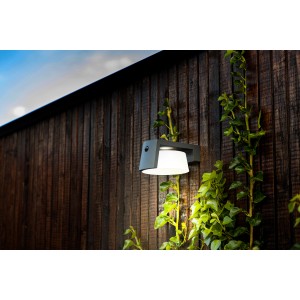 Anthrazitfarbene Lutec Solar-LED-Wandleuchte Moon für den Außenbereich, montiert an einer Holzwand.