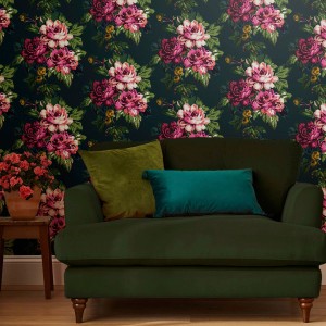 Detailaufnahme: Joules Vliestapete Invite Floral Peacock Blau mit Blumenmuster hinter Sofa.