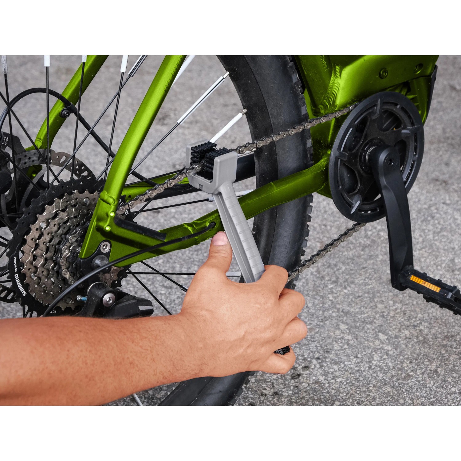 Fahrradpflege: Hand reinigt Kette eines grünen Fahrrads mit Bürste aus dem Eufab 10-teiligen Pflegeset.