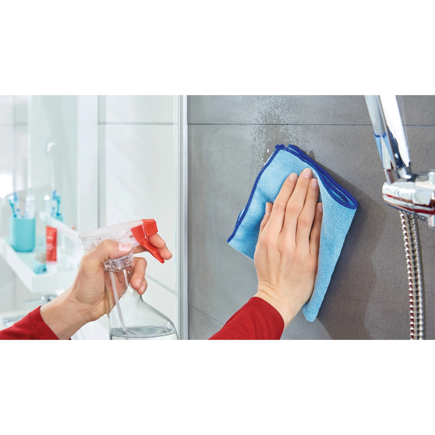 Reinigung von Fliesen mit Sprühflasche und blauem Tuch im Badezimmer.