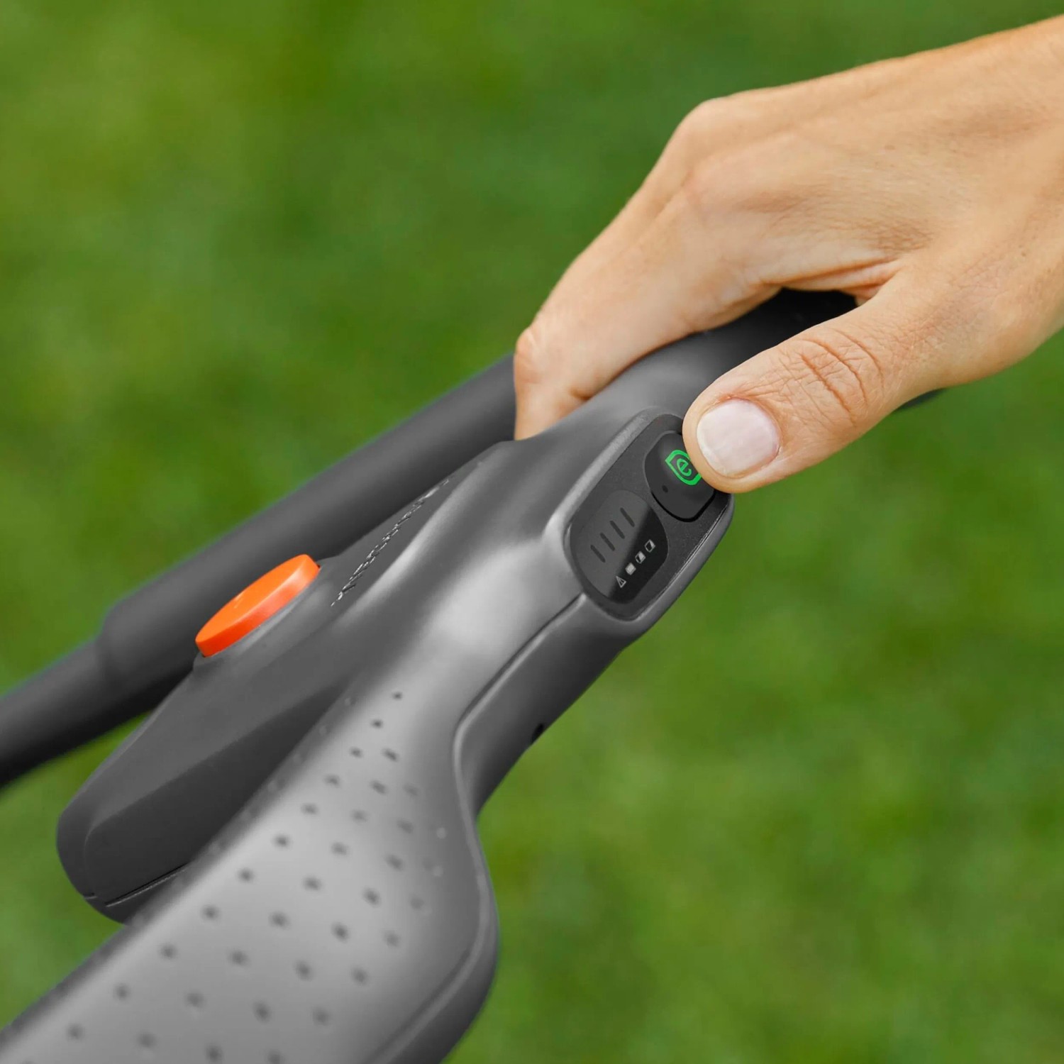 Detailaufnahme: Hand startet Gardena Akku-Rasenmäher PowerMax. Fokus auf Startknopf und Akkuanzeige.