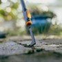 Fiskars Fugenkratzer OneClick in Aktion: Unkrautentfernung aus Pflasterfugen.