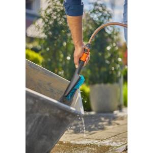 Gardena Cleansystem Handbürste Hard S mit Schlauchanschluss im Einsatz beim Reinigen einer Schubkarre.