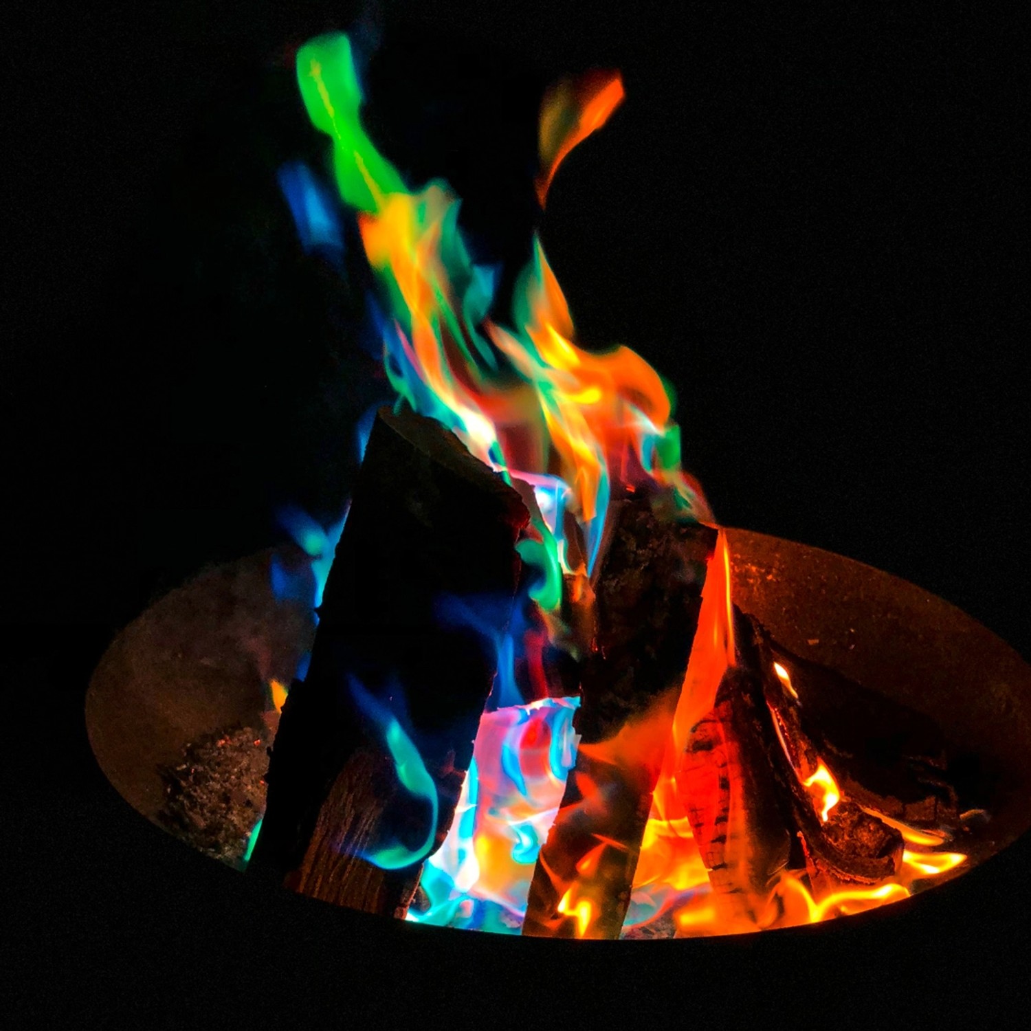 Buntes Feuer mit Feuerfarbe: Holzscheite in Rot, Orange, Gelb, Grün, Blau und Lila.