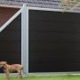 GroJaViento Zaunelement, anthrazitgrau mit silbernem Rahmen, im Garten mit Hund.