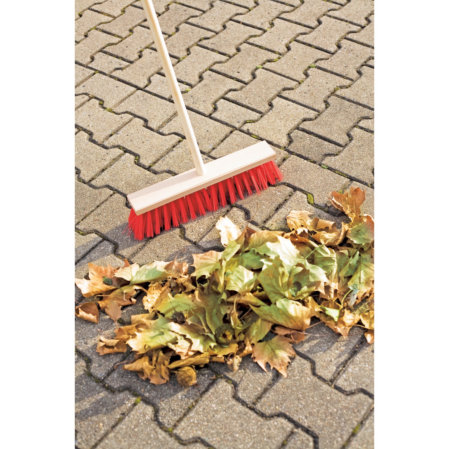 LUX Straßenbesen 40 cm mit Stiel und roten Borsten kehrt Laub auf Pflastersteinen.
