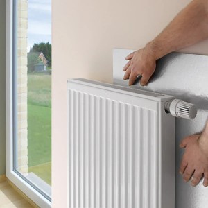 Anbringen der selbstklebenden Noma Heizkörper-Reflexionsfolie zur Dämmung hinter einem Heizkörper.