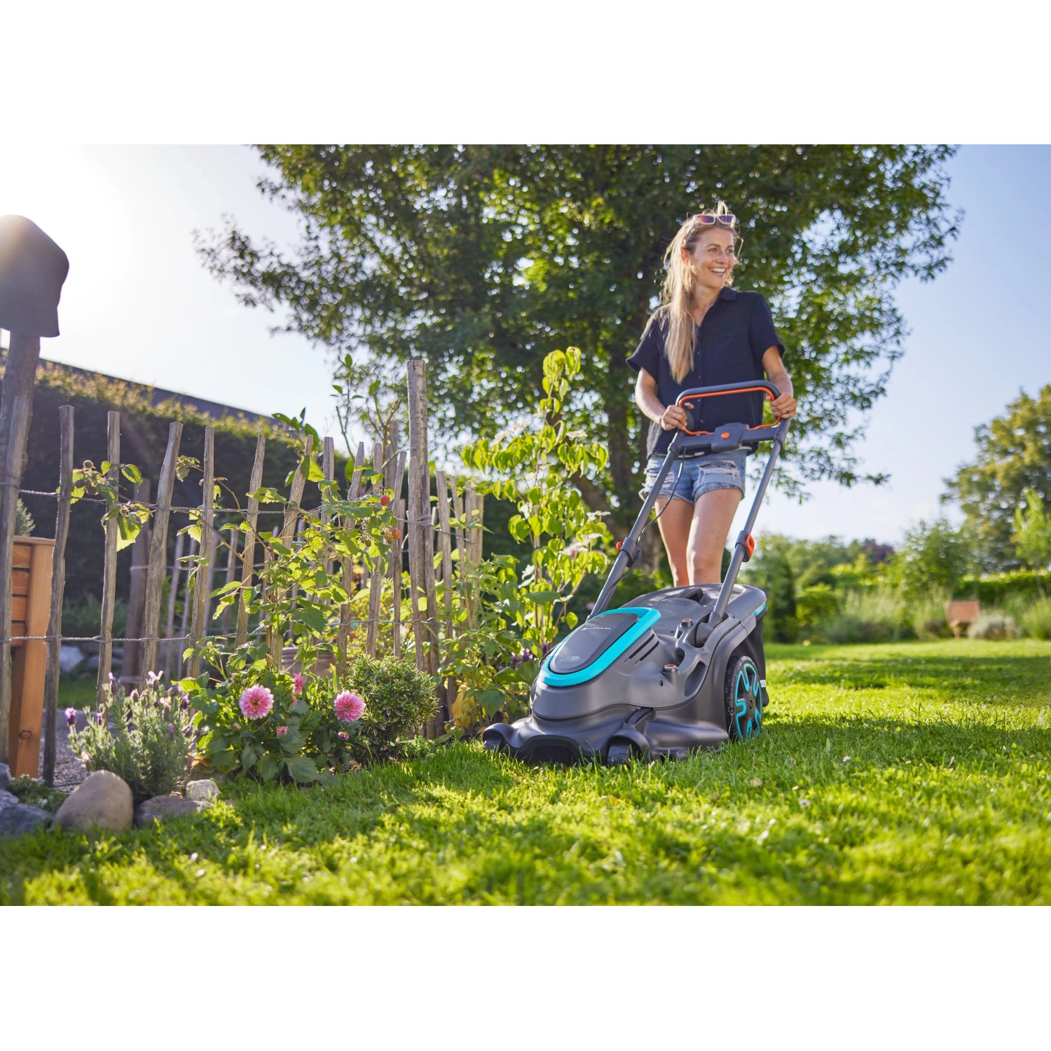 Frau mäht Rasen mit Gardena Akku-Rasenmäher PowerMax Duo 46/36 V. Inkl. 2 Akkus.