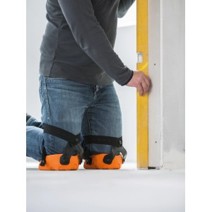 Handwerker mit orangenen LUX Knieschoner Comfort beim Nivellieren einer Wand.