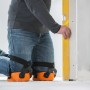 Handwerker mit orangenen LUX Knieschoner Comfort beim Nivellieren einer Wand.