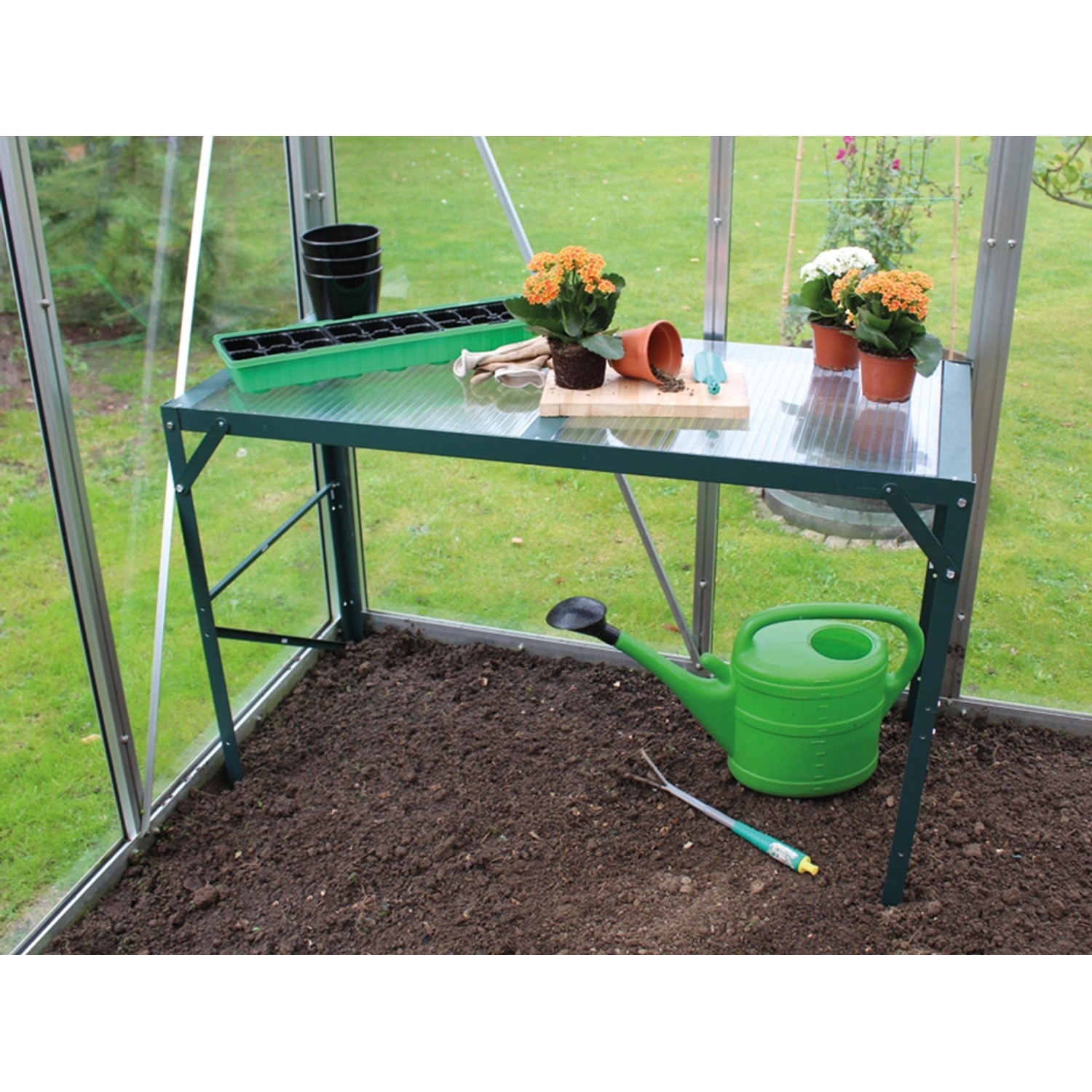 Vitavia Alutisch Smaragd 121x54cm mit Ablage im Gewächshaus mit Gießkanne und Pflanzen.