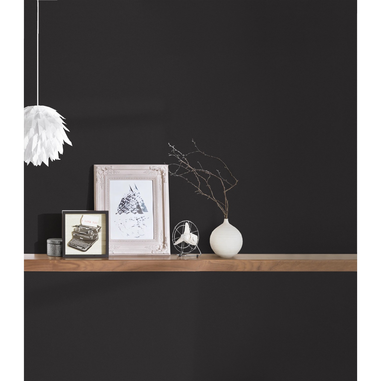 Schwarze Vliestapete Trendwall 2 Uni, kombiniert mit Deko-Elementen auf einem Holzregal.