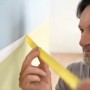 Mann klebt mit Tesa Malerband Professional eine Wand ab. Das gelbe Klebeband sorgt für scharfe Farbkanten.