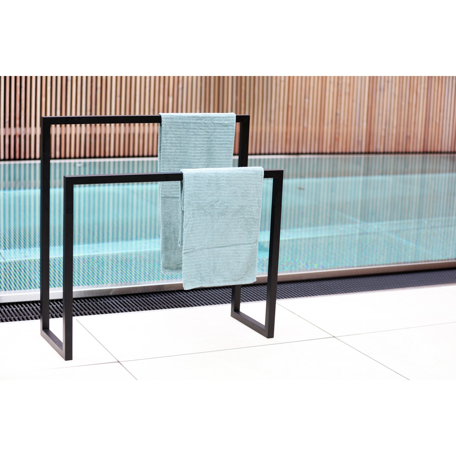 Schwarzer Handtuchhalter Slim Line mit zwei hellblauen Handtüchern vor Pool.