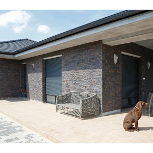 Hauswand mit Stegu Verblender Nepal Grau, graue Rollläden und Hund.