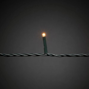 Nahaufnahme einer leuchtenden bernsteinfarbenen Konstsmide LED an einem dunklen Kabel für Außen-Lichterketten.