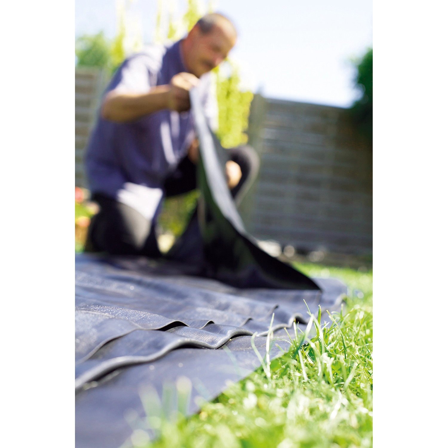 Schwarze Heissner PVC Teichfolie (1 mm) wird im Garten verlegt.