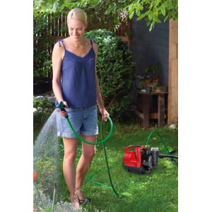 Frau bewässert Garten mit Einhell Hauswasserautomat GC-AW 6333. Elektro-Pumpe mit Schlauch.