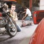 Werkstatt mit LUX Abdeckvlies: Motorrad, Auto und Mechaniker auf grauem Schutzvlies.