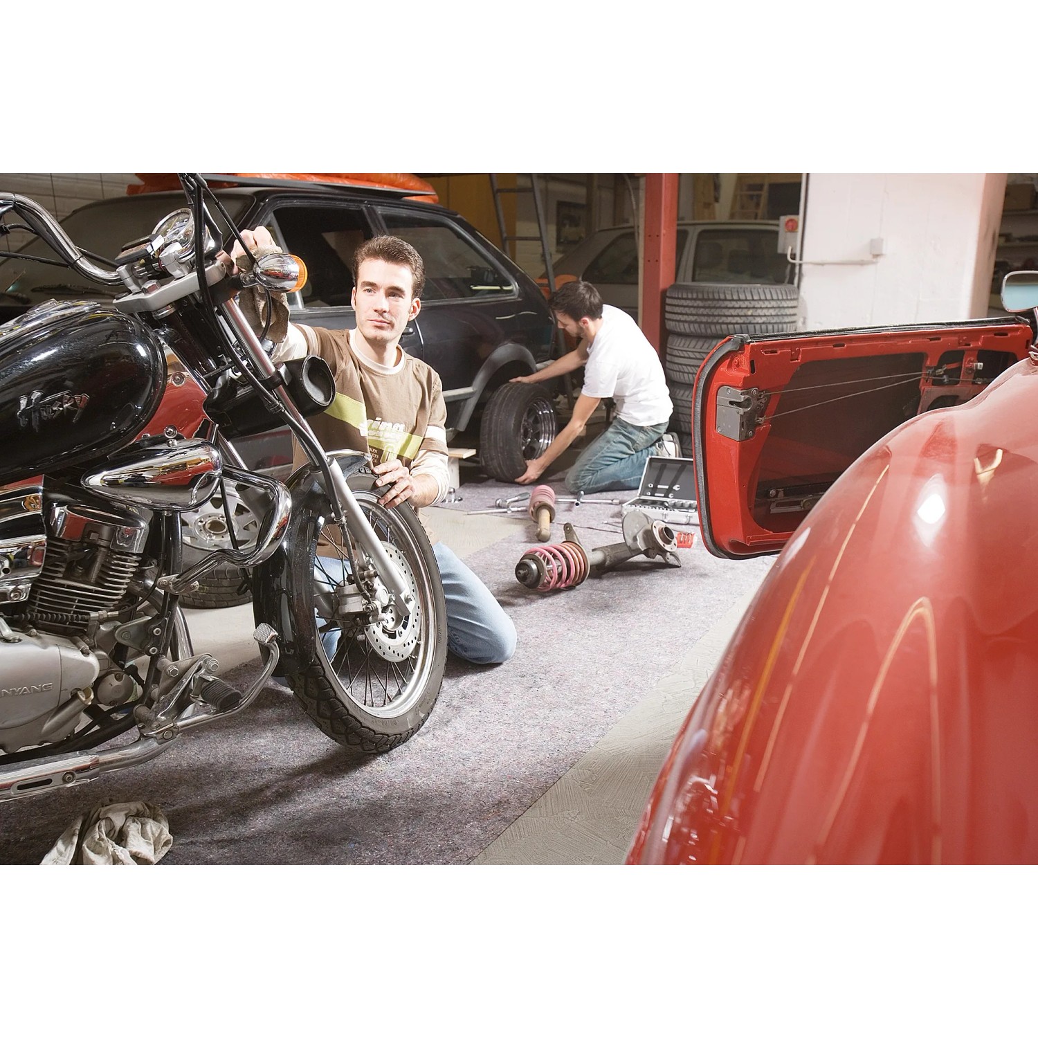 Werkstatt mit LUX Abdeckvlies: Motorrad, Auto und Mechaniker auf grauem Schutzvlies.