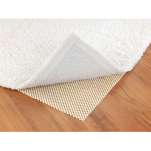 Beige Wenko Anti-Rutsch-Matte (150x50 cm) unter einem Teppich auf Holzboden.