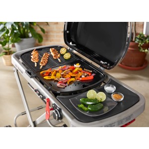 Weber Grillplatte mit erhöhtem Rand auf Grill mit Grillgut und Gemüse.